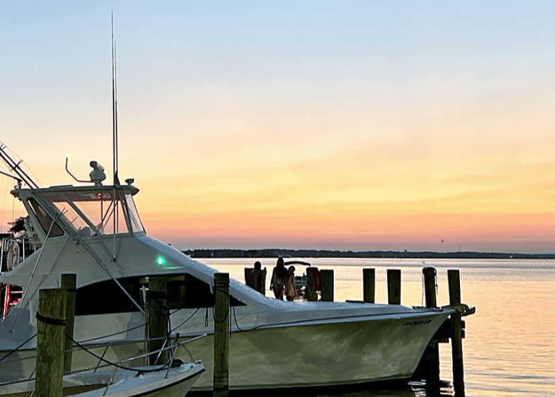 Boat docked at a pier during sunset with a colorful sky.