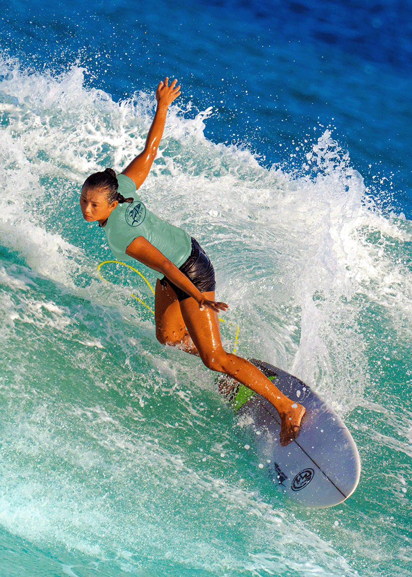 Person surfing on a wave with clear blue water