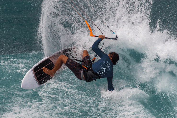 Person windsurfing on a wave with a sail and board.