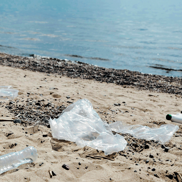 Plastic waste on a sandy beach with water in the background